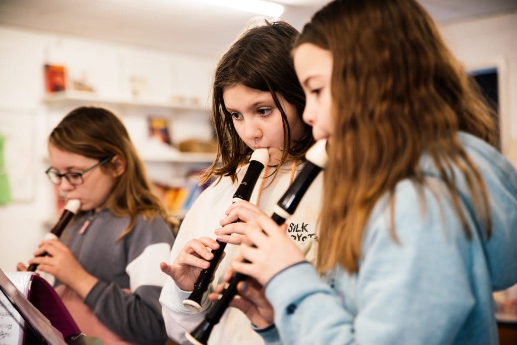 three young people playing the recorder