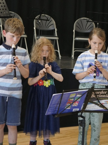 3 young children play the recorder