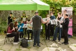 a group of young musicians under a gazebo play outside
